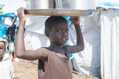 Criança carrega água em um local de proteção civil de Tomping, Sudão do Sul. Foto: ONU/Eskinder Debebe.