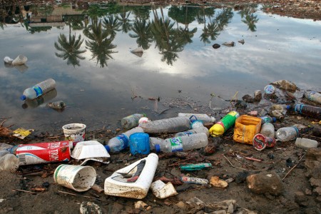 Garrafas de plástico e resíduos de lixo as margens de um rio. Foto: ONU/Martine Perret.